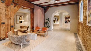 Un intérieur spacieux avec des poutres en bois, un coin salon avec des chaises et un canapé, une grande fenêtre et une vue sur une autre pièce.