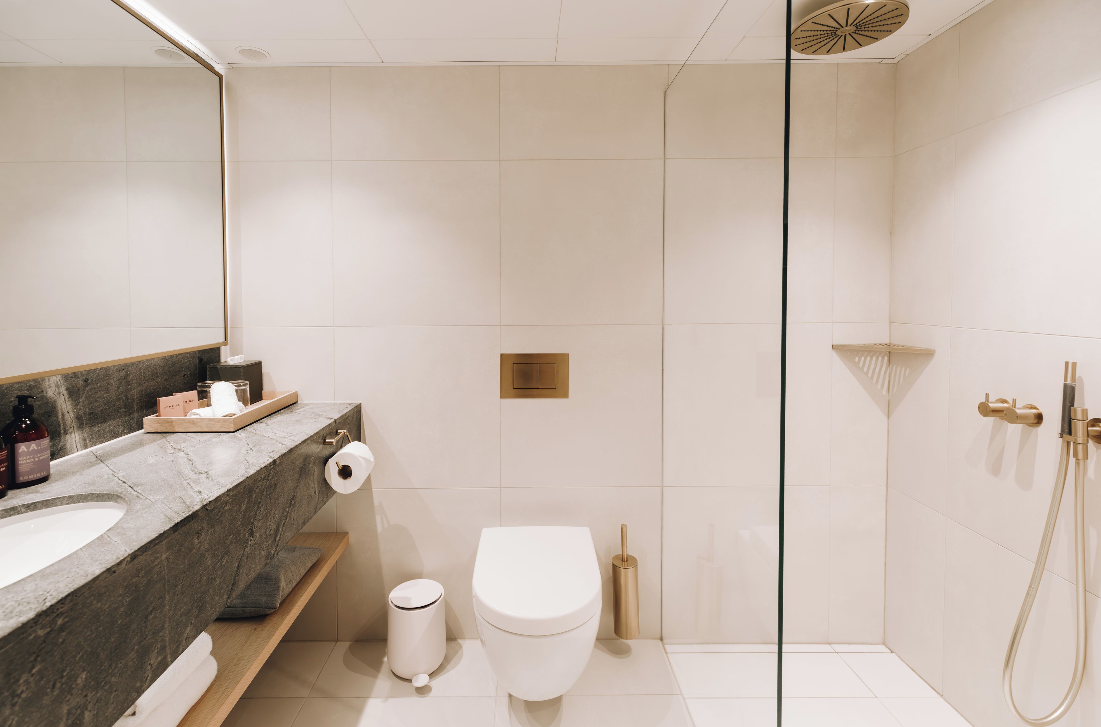 A modern bathroom with a marble sink, a toilet, and a shower area.