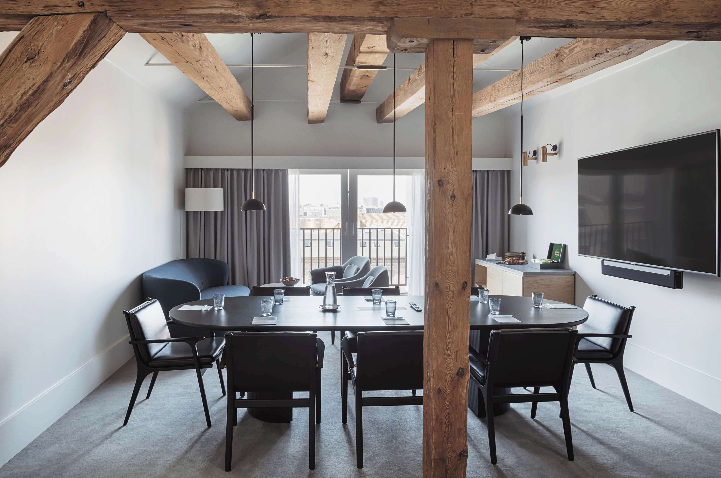 Un comedor moderno con techo de madera, un televisor grande y vistas de la ciudad a través de amplias ventanas.