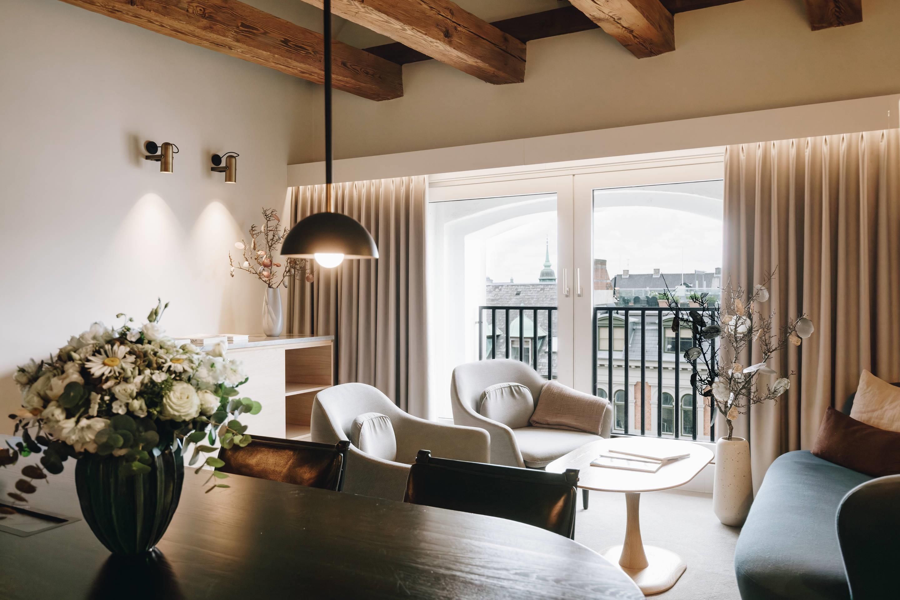 Una sala de estar moderna con una mesa de comedor, dos sillas, un sofá y un balcón con cortinas.