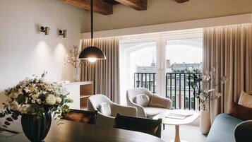 Una sala de estar moderna con una mesa de comedor, dos sillas, un sofá y un balcón con cortinas.