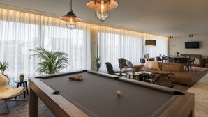 A modern living room with a pool table, comfortable seating, and large windows with sheer curtains. - PREMIER SUITES PLUS Antwerp (Antwerp)