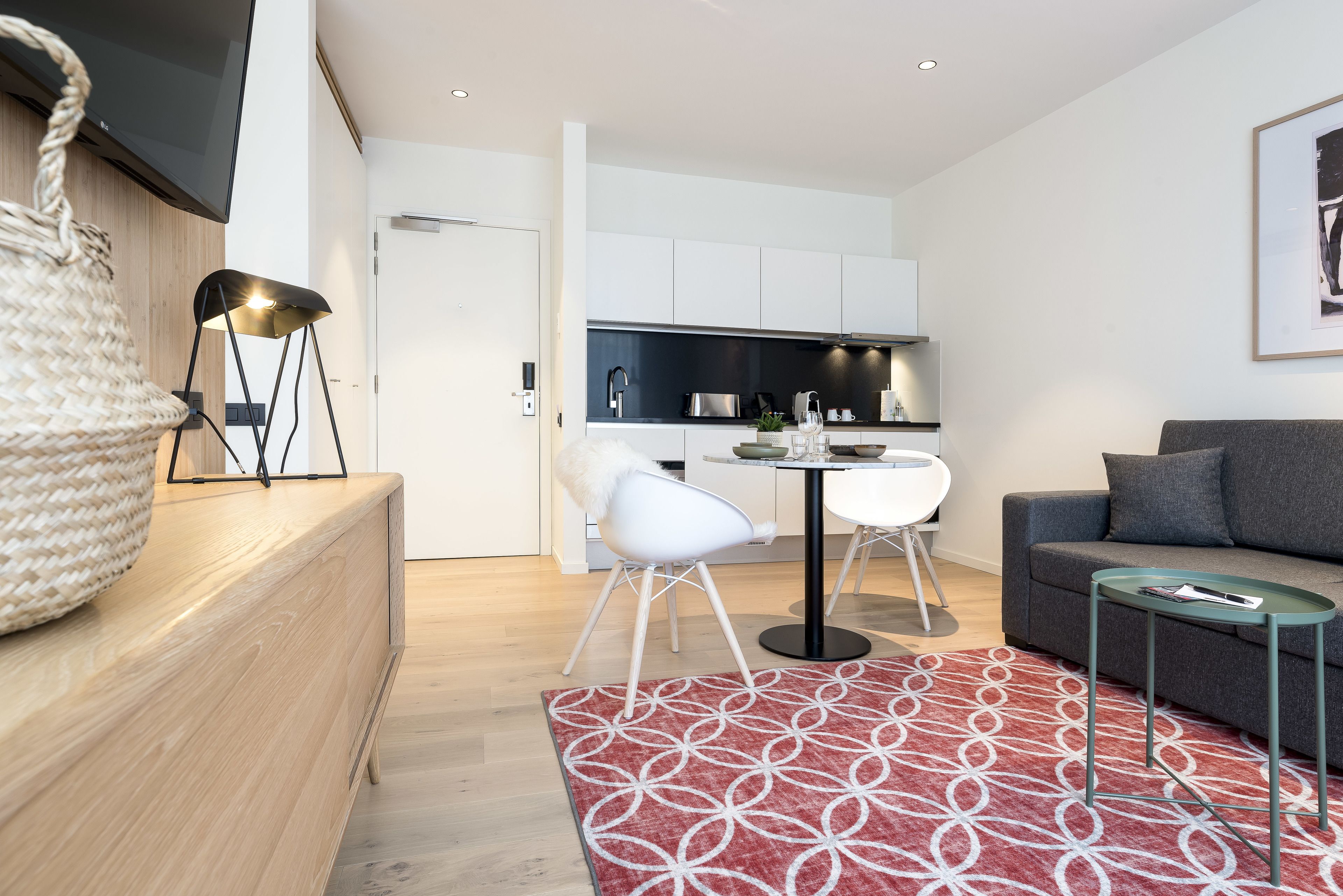 A modern living room with a sofa, a coffee table, and a dining area with a table and chairs.