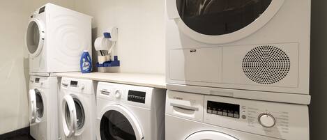 A laundry area with multiple washing machines and a detergent dispenser.