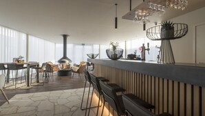 A modern kitchen with a bar area, wooden flooring, and large windows. - PREMIER SUITES PLUS Antwerp (Antwerp)