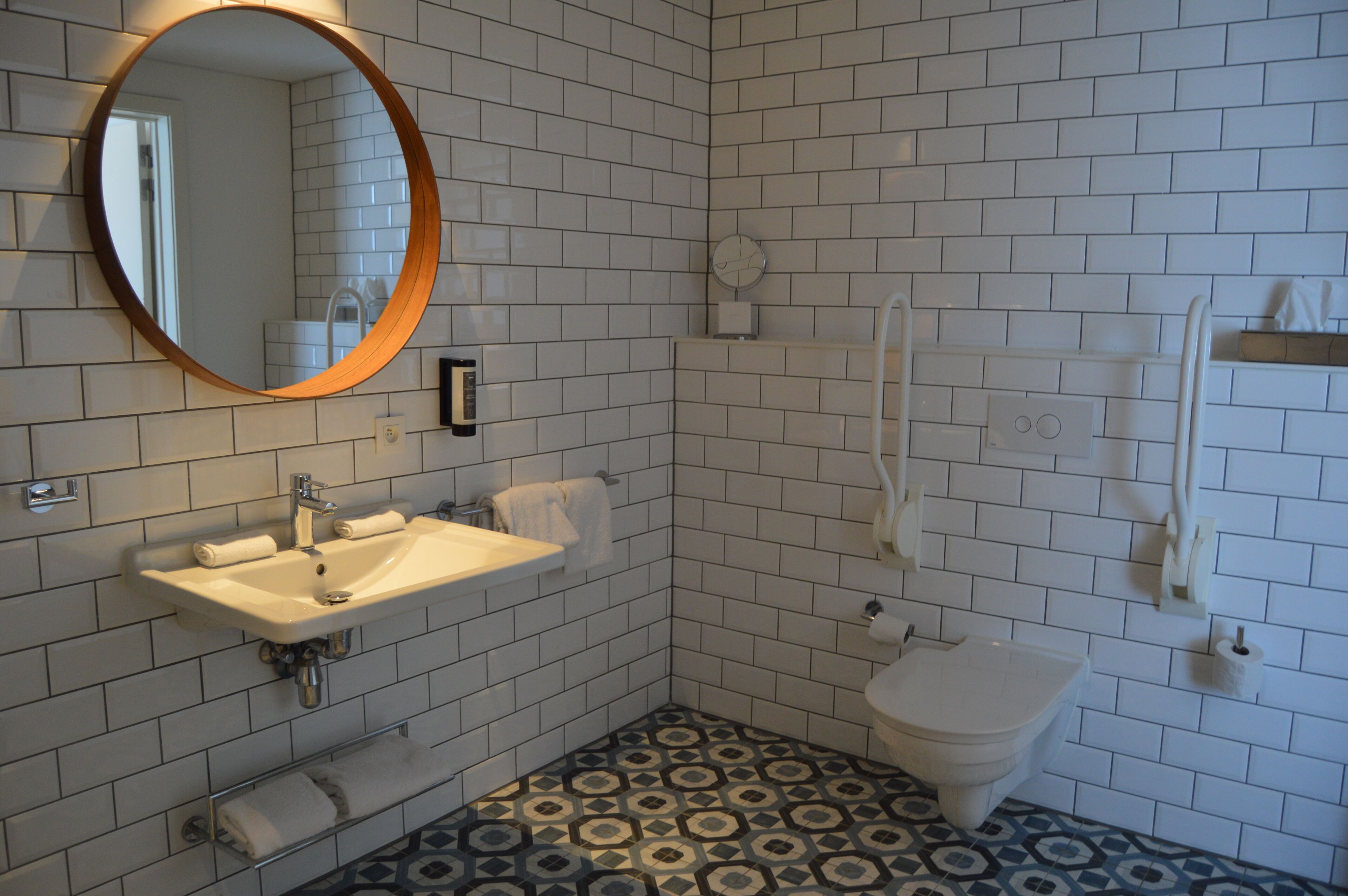 A bathroom with a sink, mirror, toilet, and towel rack.