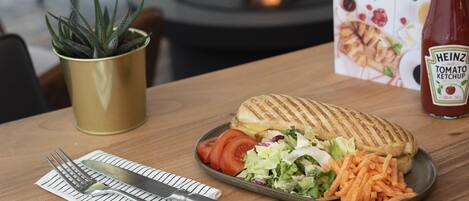 A meal with a grilled sandwich, salad, and carrots on a plate, a bottle of Heinz tomato ketchup, a potted plant, and a 'Good Morning' sign.
