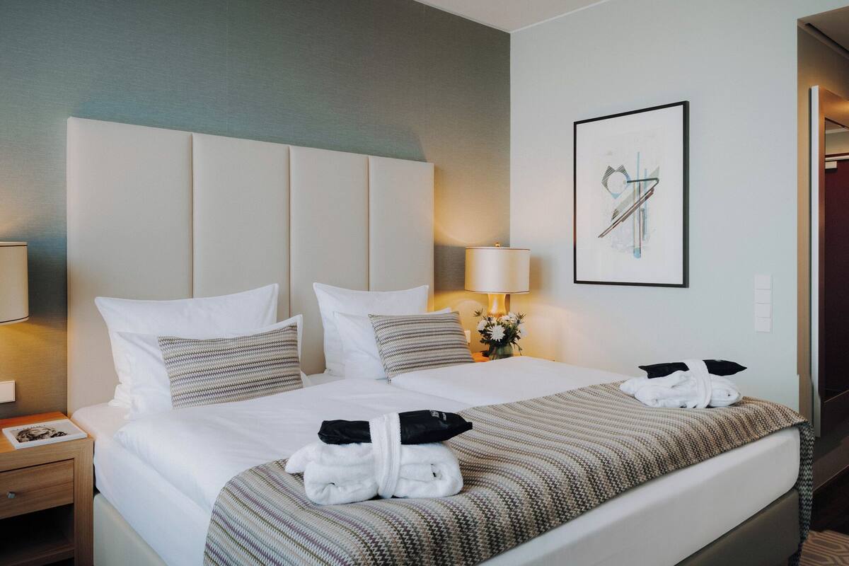 A hotel room with a large bed, a nightstand, a lamp, and a framed picture on the wall.