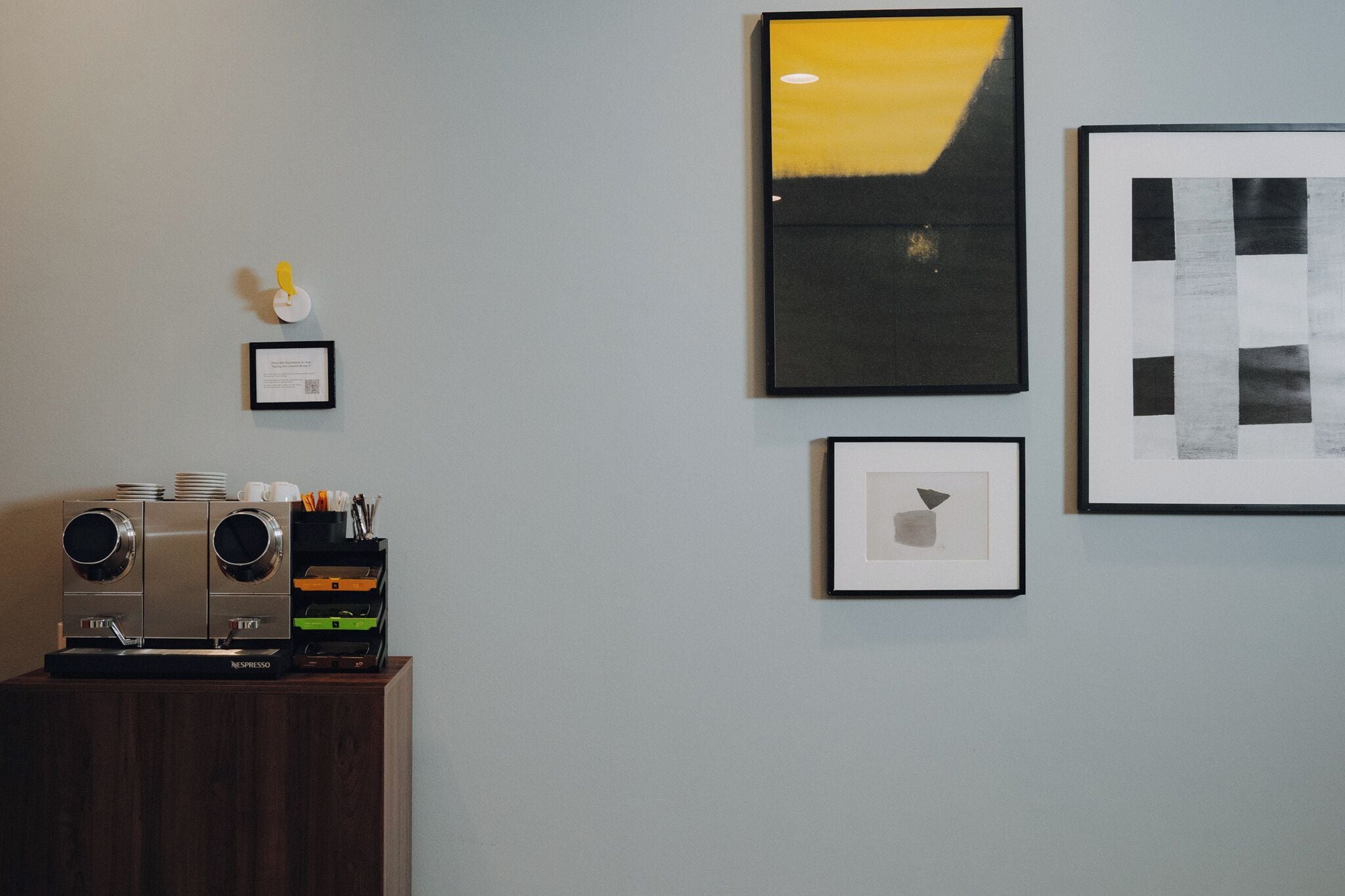 Una pared decorada con cuadros, una cafetera y una pequeña placa.
