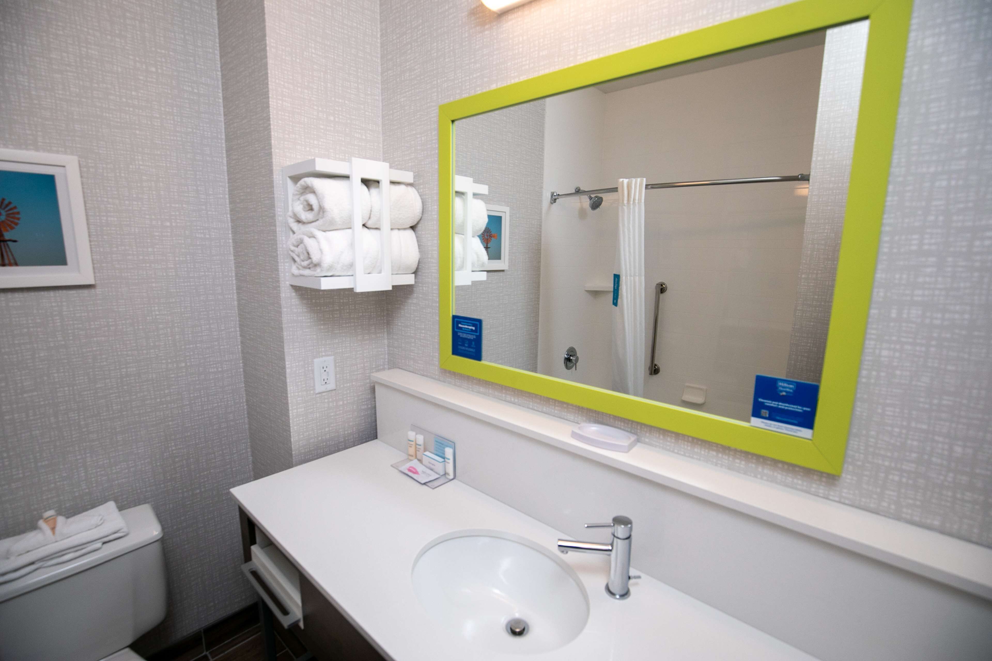 A bathroom with a white sink, a mirror with a yellow frame, and a towel rack with towels.