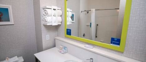 A bathroom with a white sink, a mirror with a yellow frame, and a towel rack with towels.