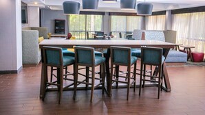 A modern dining area with a large table, bar stools, and pendant lighting. - Hampton Inn Pickwick Dam-At Shiloh Falls (Counce)