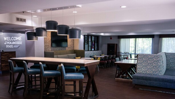 A modern hotel lobby with a central bar area, seating arrangements, and a welcoming sign. - Hampton Inn Pickwick Dam-At Shiloh Falls (Counce)