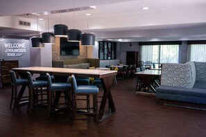 A modern hotel lobby with a central bar area, seating arrangements, and a welcoming sign. - Hampton Inn Pickwick Dam-At Shiloh Falls (Counce)