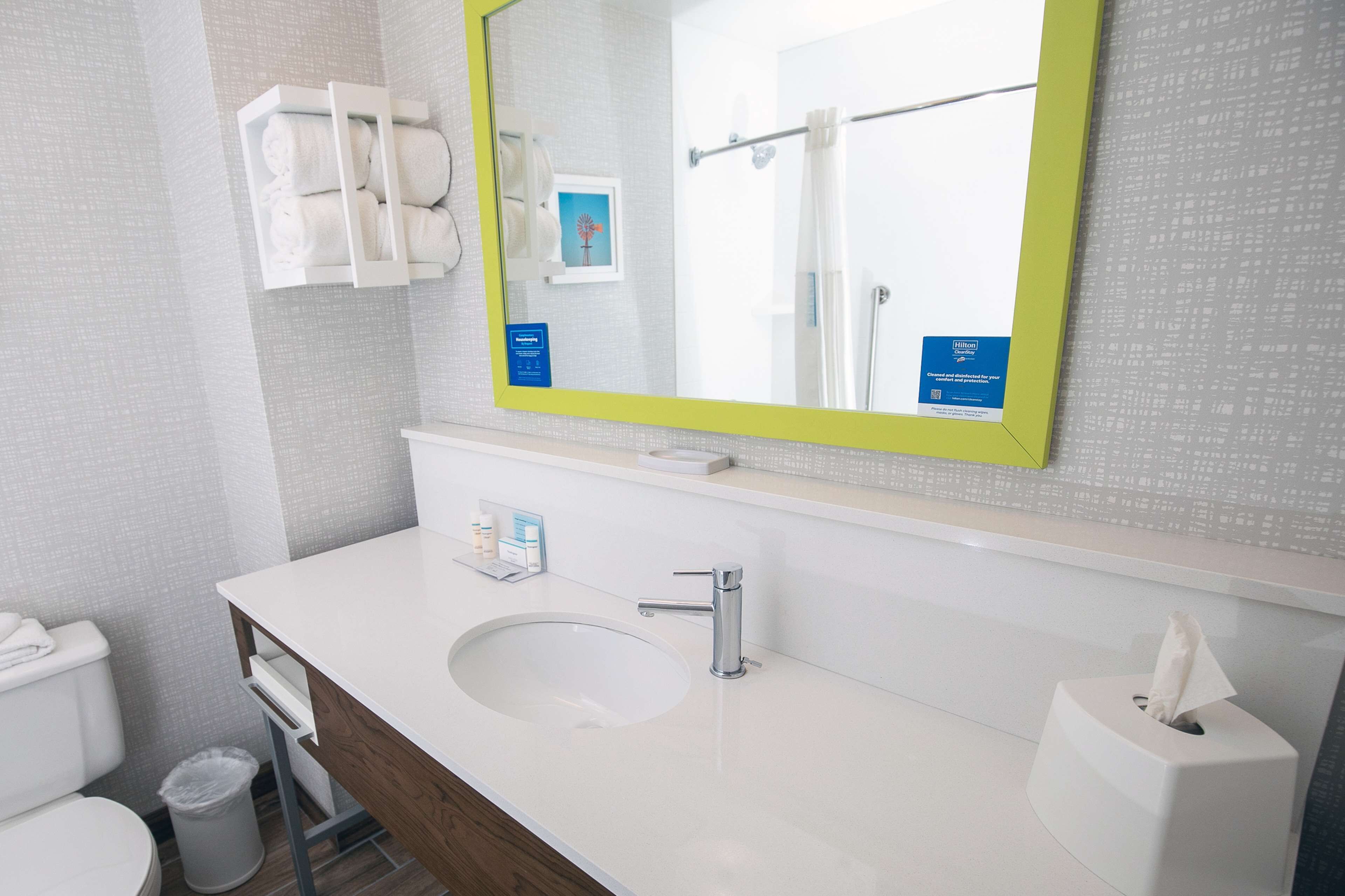 A modern bathroom with a white sink, a mirror with a yellow frame, and a towel rack.