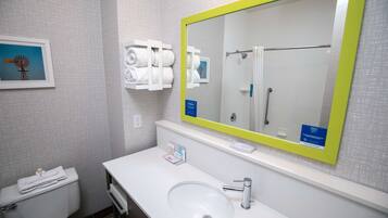 A bathroom with a white sink, a mirror with a yellow frame, and a towel rack with neatly folded towels.