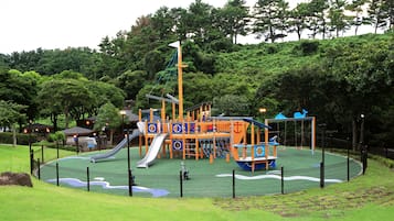 Explore a playground with slides, climbing frames, and a ship-themed play area, surrounded by lush greenery.