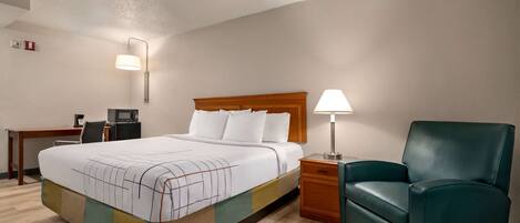 A hotel room with a bed, a desk, a chair, and a nightstand.