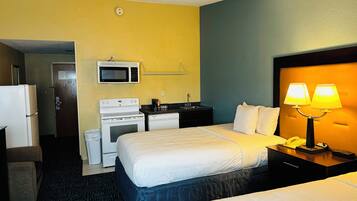 Une chambre d’hôtel avec deux lits, un four à micro-ondes, une cuisinière, un évier et un téléphone.