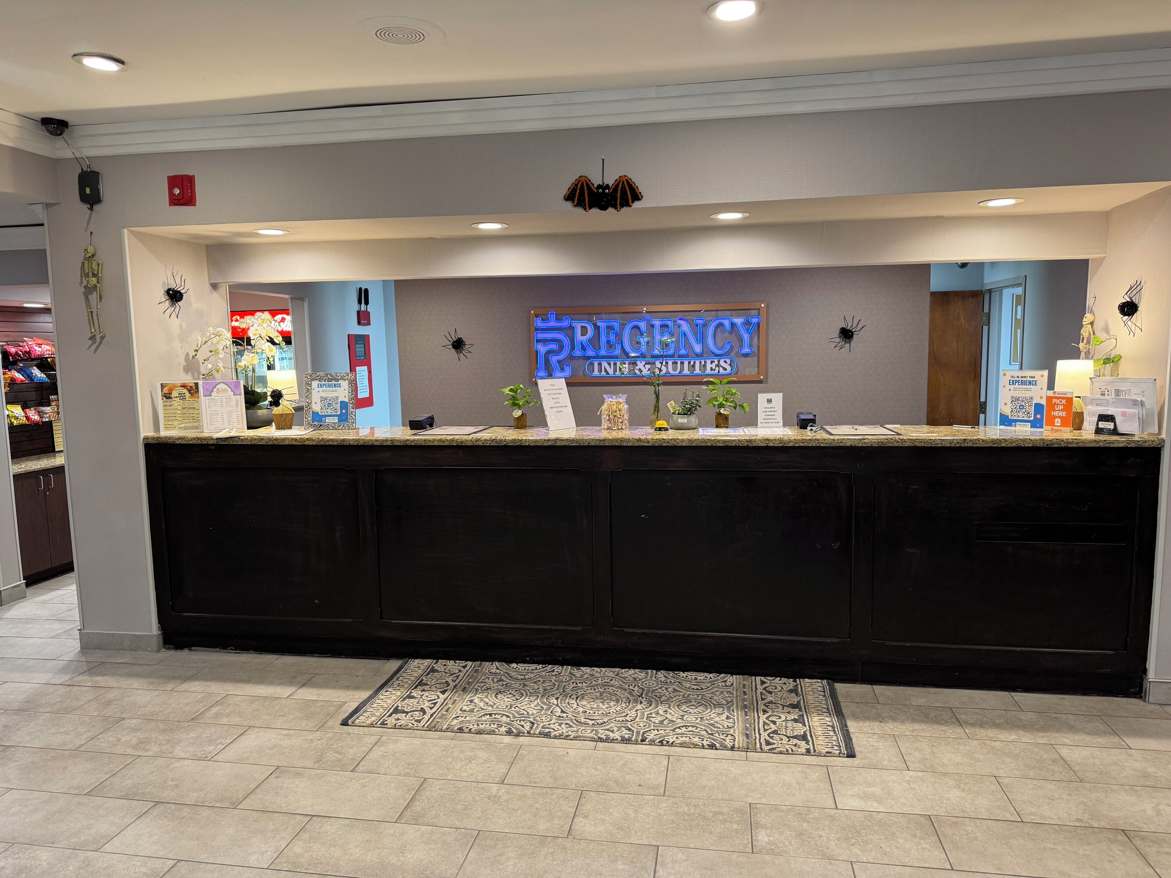 A reception desk with a sign reading 'REGENCY INN & SUITES' and a counter with various items.