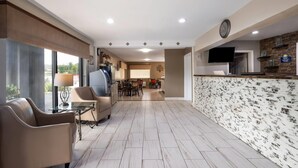 A modern hotel lobby with a reception desk, seating area, and a dining space.