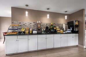 A modern kitchen with white cabinets, a brick backsplash, and a variety of appliances including a coffee maker, toaster, and refrigerator.