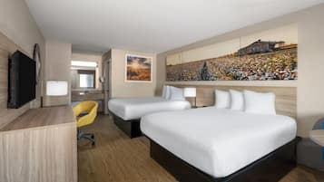 Une chambre d’hôtel avec deux lits, un bureau, une chaise et un grand tableau au mur.