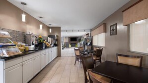A modern kitchen with a long counter, built-in appliances, and a dining area with a table and chairs.