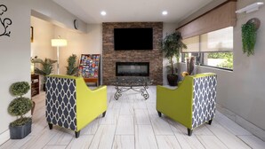 A living room with a stone fireplace, a flat-screen TV, and two yellow armchairs.