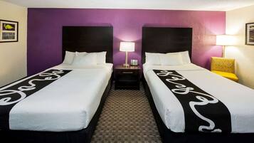 A hotel room with two beds, purple walls, and a patterned carpet.