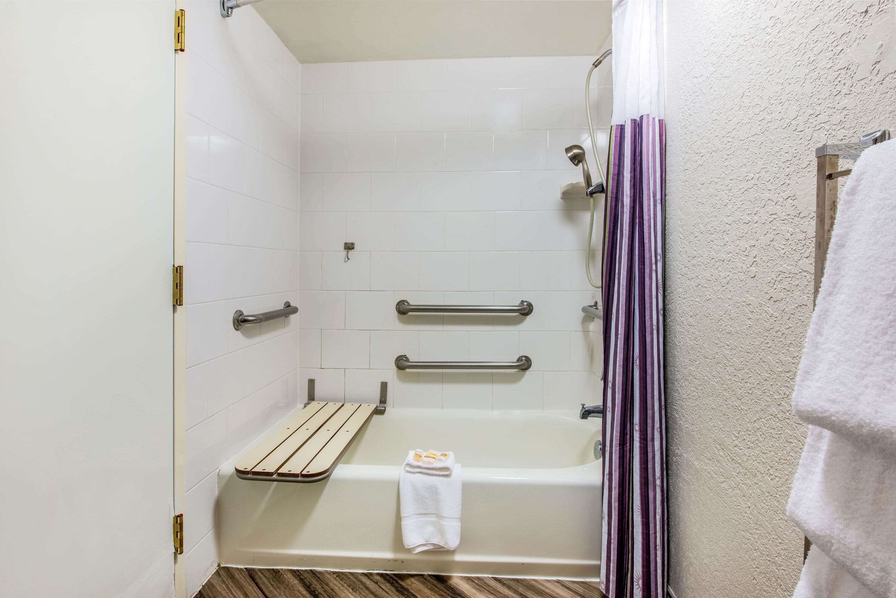 Une salle de bain équipée d’une baignoire, d’une douche, d’un porte-serviettes et d’une barre d’appui.