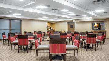 A conference room with multiple tables and chairs, a podium, and a vending machine.