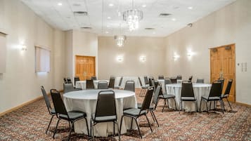 A conference room with round tables and chairs, a patterned carpet, and a chandelier.