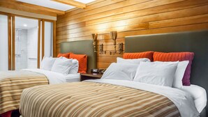 Habitación de hotel con dos camas, paneles de madera en las paredes, un tragaluz y una mesita de noche con un reloj.