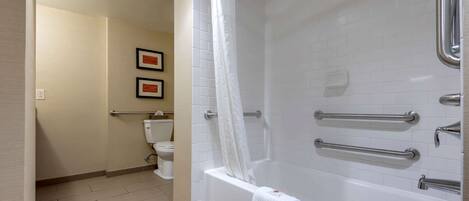A bathroom with a bathtub, a toilet, and a shower curtain.
