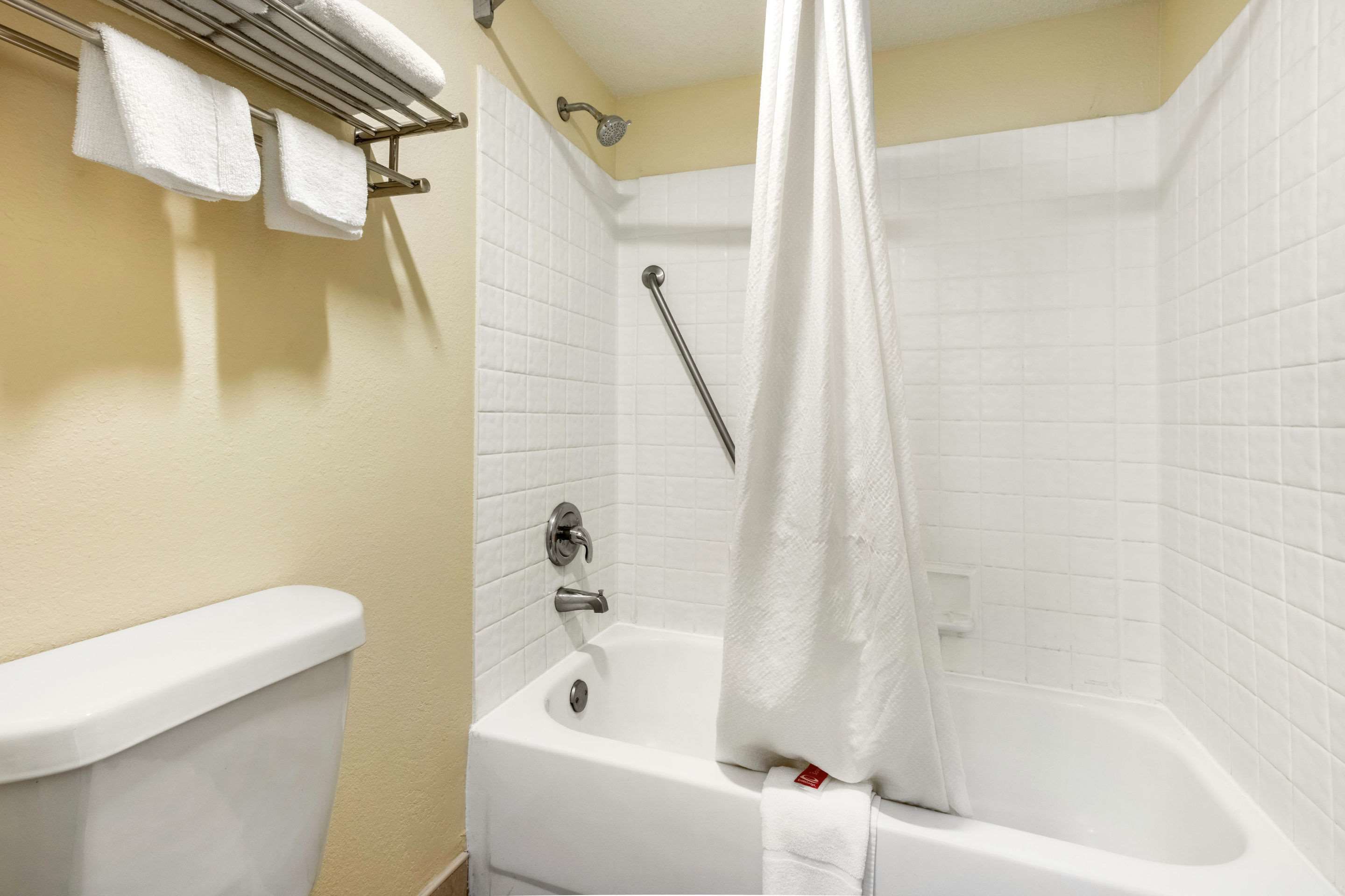 Une salle de bain avec une baignoire, un rideau de douche et un porte-serviettes avec des serviettes.
