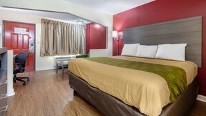 A hotel room with a large bed, a desk with a chair, a red door, and a window with curtains. - Econo Lodge Chattanooga Northeast - Ooltewah (Chattanooga)