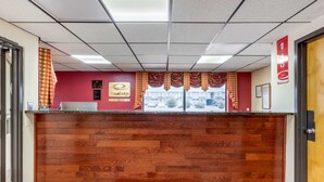 A reception desk with a wooden finish, a red wall with a plaque, and a window with curtains. - Econo Lodge Chattanooga Northeast - Ooltewah (Chattanooga)