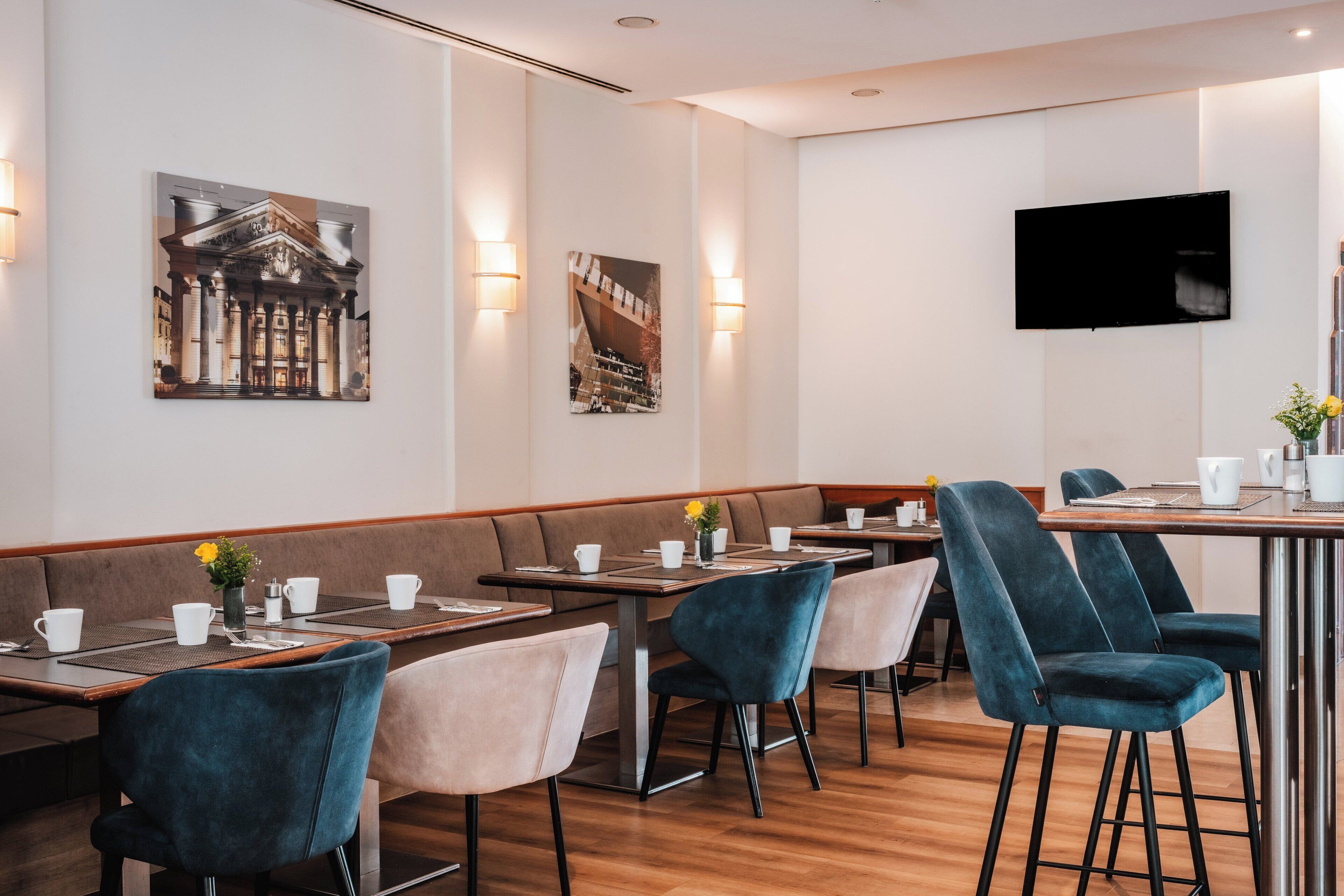 Un restaurante moderno con mesas de madera, cabinas acolchadas y un televisor de pantalla plana en la pared.