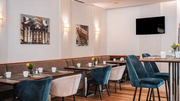 Un restaurante moderno con mesas de madera, cabinas acolchadas y un televisor de pantalla plana en la pared.