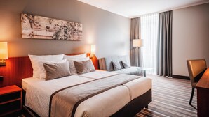 Habitación de hotel con una cama grande, dos mesitas de noche con lámparas, un escritorio y una silla.