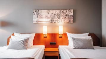 A hotel room with two beds, a wooden headboard, a nightstand, and a wall-mounted artwork.
