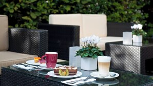 Un espacio de estar al aire libre con muebles de mimbre, una mesa de vidrio y una planta en maceta.