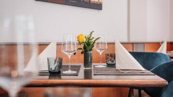 Una mesa de comedor dispuesta con vasos transparentes, un jarrón con una flor amarilla y una servilleta.