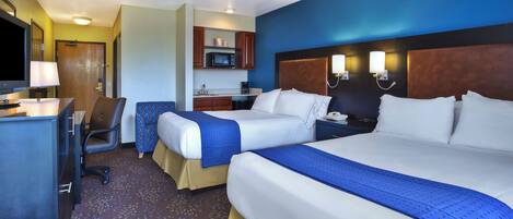 A hotel room with two beds, a desk, a chair, a microwave, and a ceiling fan.