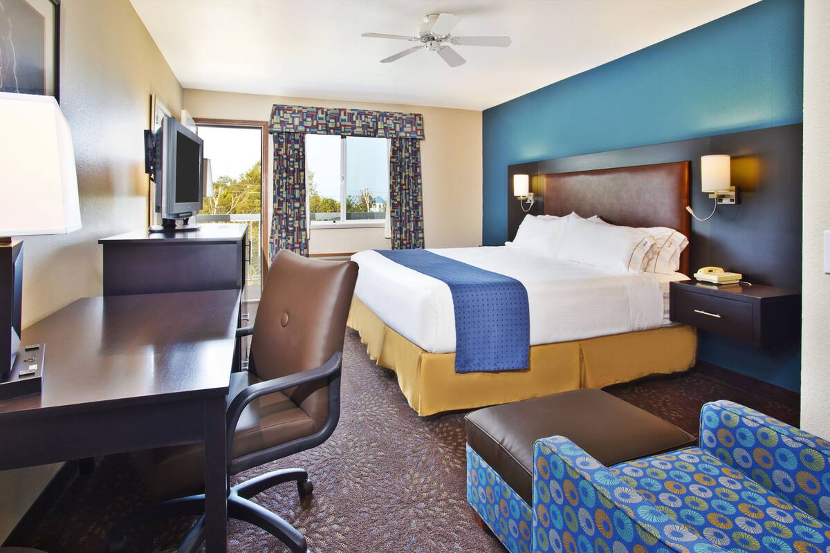 Una habitación de hotel con cama, escritorio, silla y televisor.