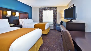A hotel room with two beds, a sofa, a TV, and a desk.