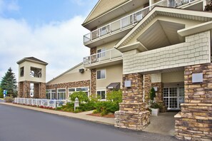 A multi-story hotel with a stone facade, balconies, and a small tower-like structure.