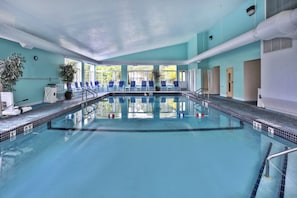 Una piscina con borde de azulejos, una silla de salvavidas y una planta en maceta.