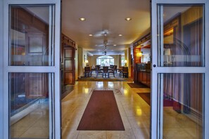 A hotel lobby with a central seating area, a reception desk, and a view of the outdoors through large windows.